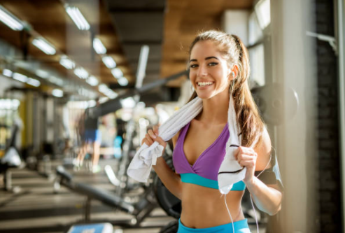 Frau im Fitnessstudio mit Handtuch und Wasserflasche